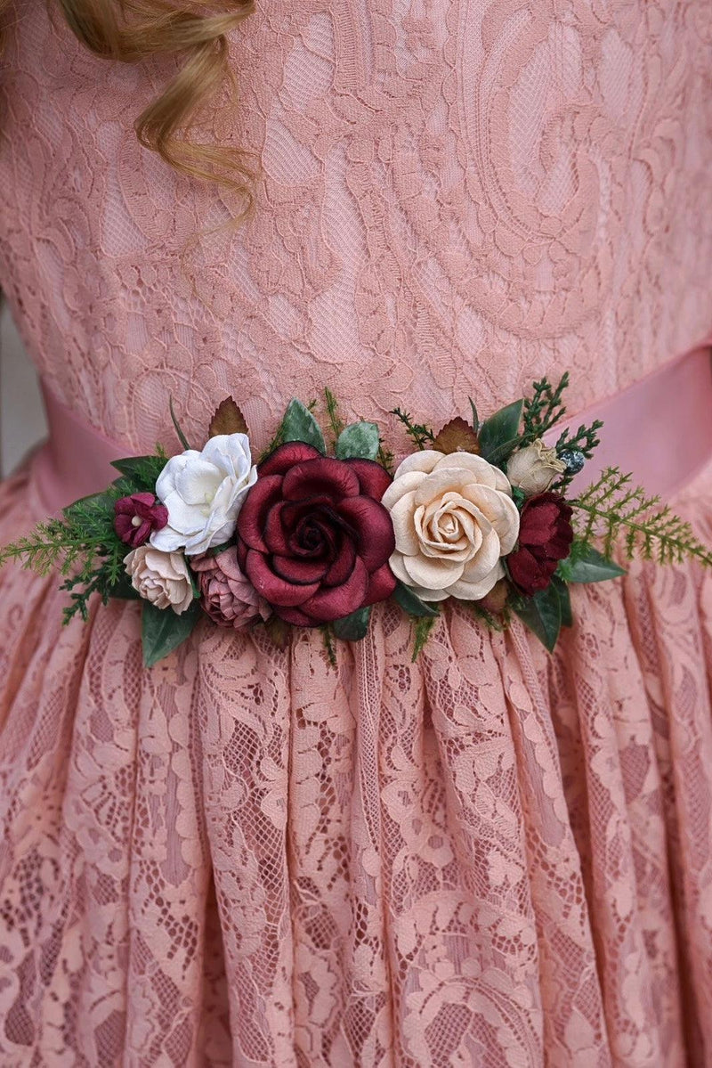 Pink lace dress with a floral belt featuring red, white, and green flowers.