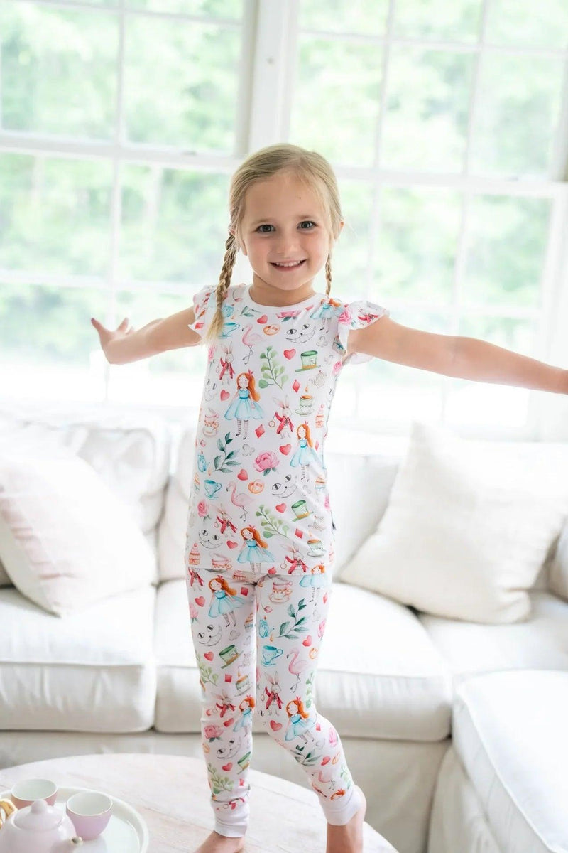 Adventures with Alice 2-piece bamboo sleepwear set. Girl modeling Alice in Wonderland print bamboo pajamas, shown in soft pink two-piece set.