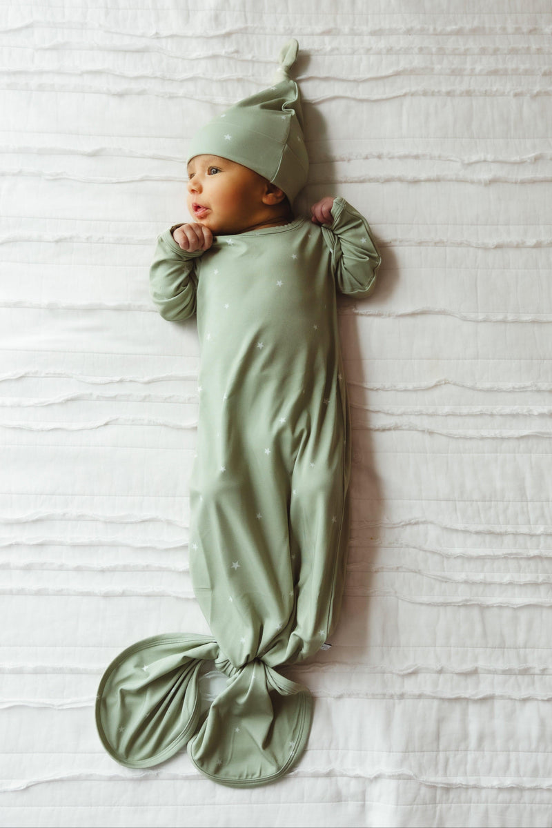 Newborn baby wearing sage green star-print bamboo knotted gown, lying peacefully in full-length view — cozy, gender-neutral sleepwear ideal for first outfits or gifting.

