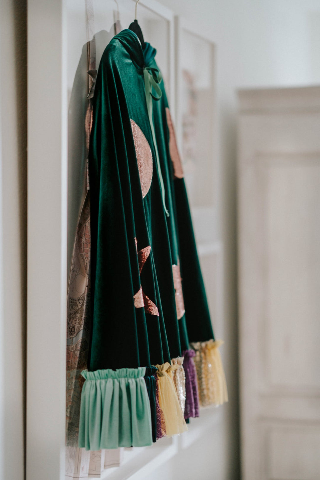Flat lay side view of green velvet sanderson sister hocus pocus witch costume cape with moon and star sequins.