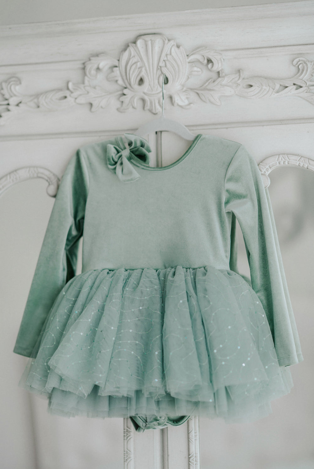 Willow green tutu dress hanging, showing full layered sparkle tulle skirt and soft bodice.