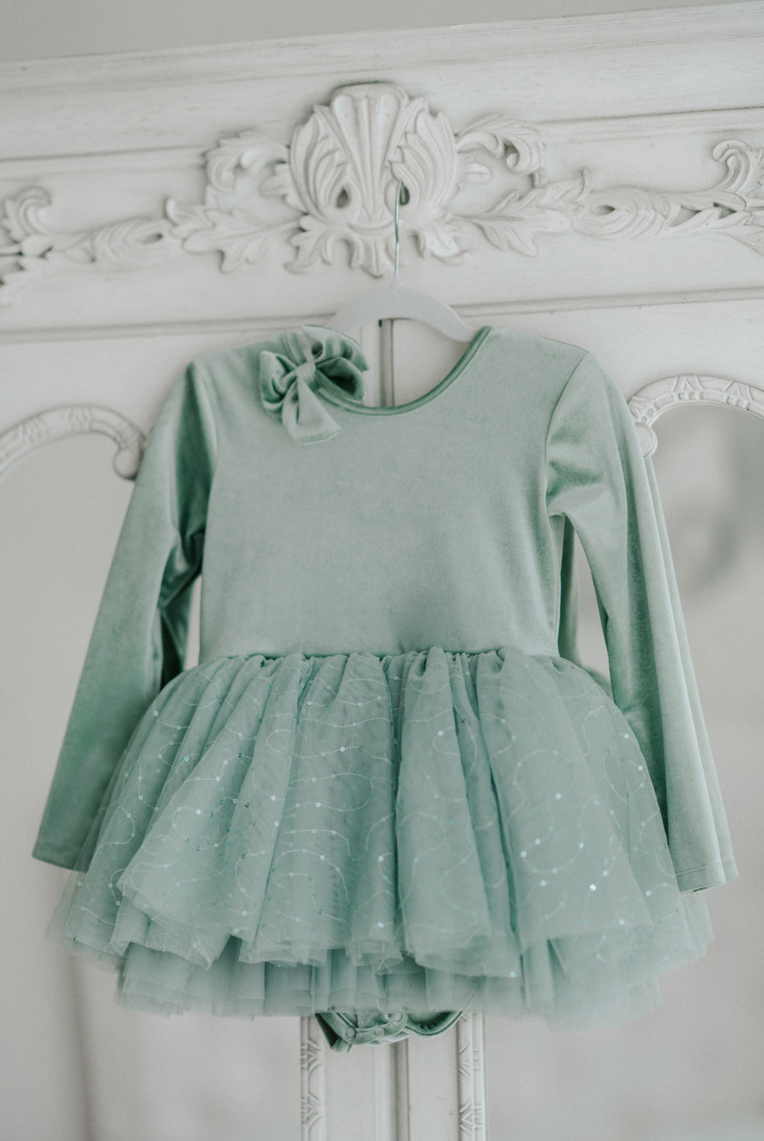 Willow green tutu dress hanging, showing full layered sparkle tulle skirt and soft bodice.