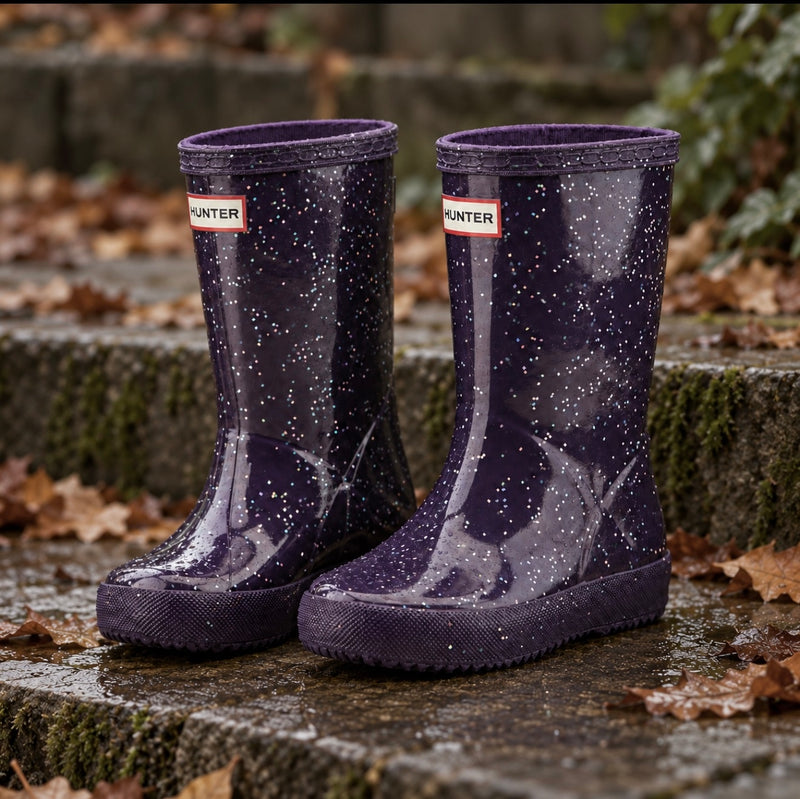 Hunter Boots Little Kids First Giant Glitter dark purple waterproof rain boots on wet stone steps in an autumn setting