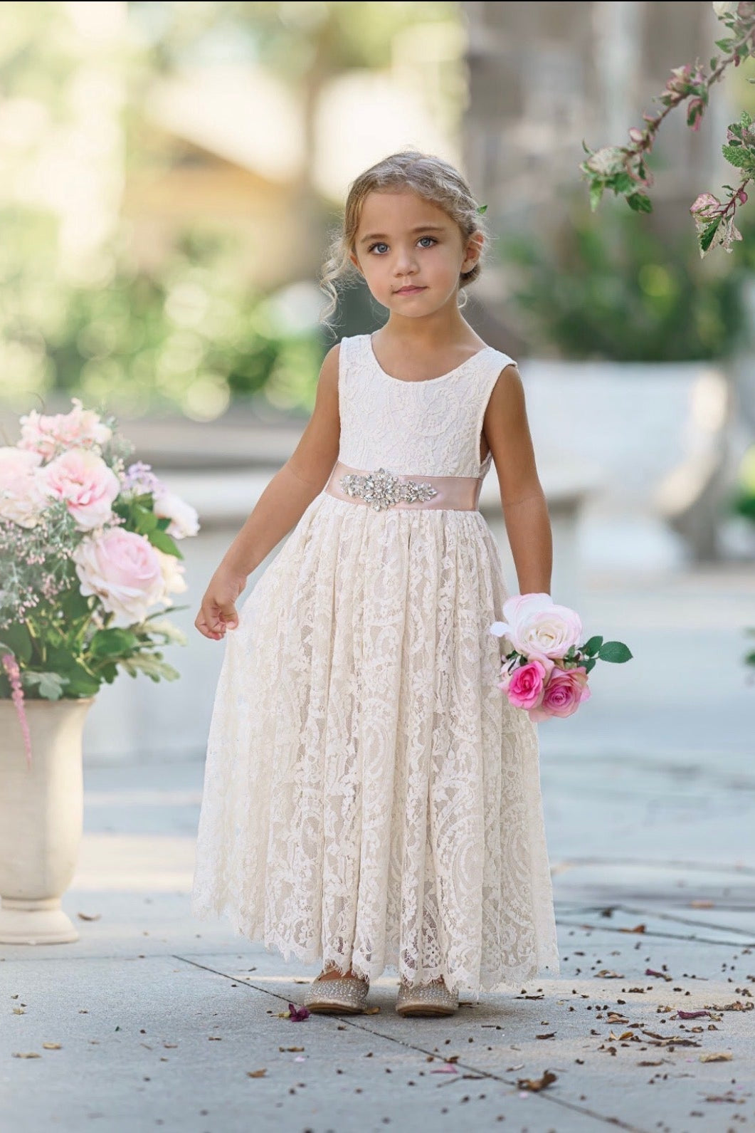 Little girl wearing a sleeveless, ankle length ivory lace flower girl dress