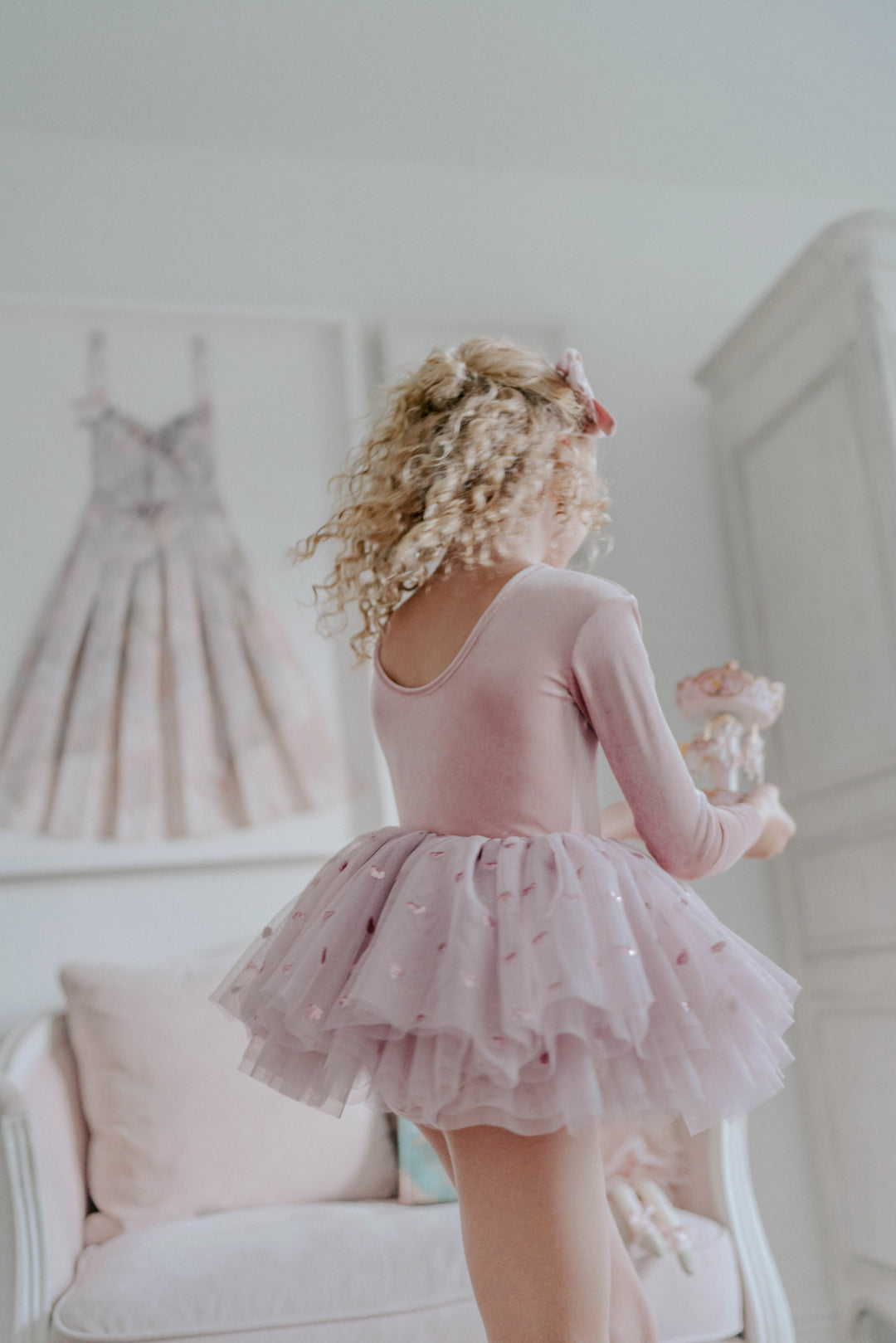 Girl twirling in rosewood heart sequin tulle tutu dress in softly lit indoor setting.