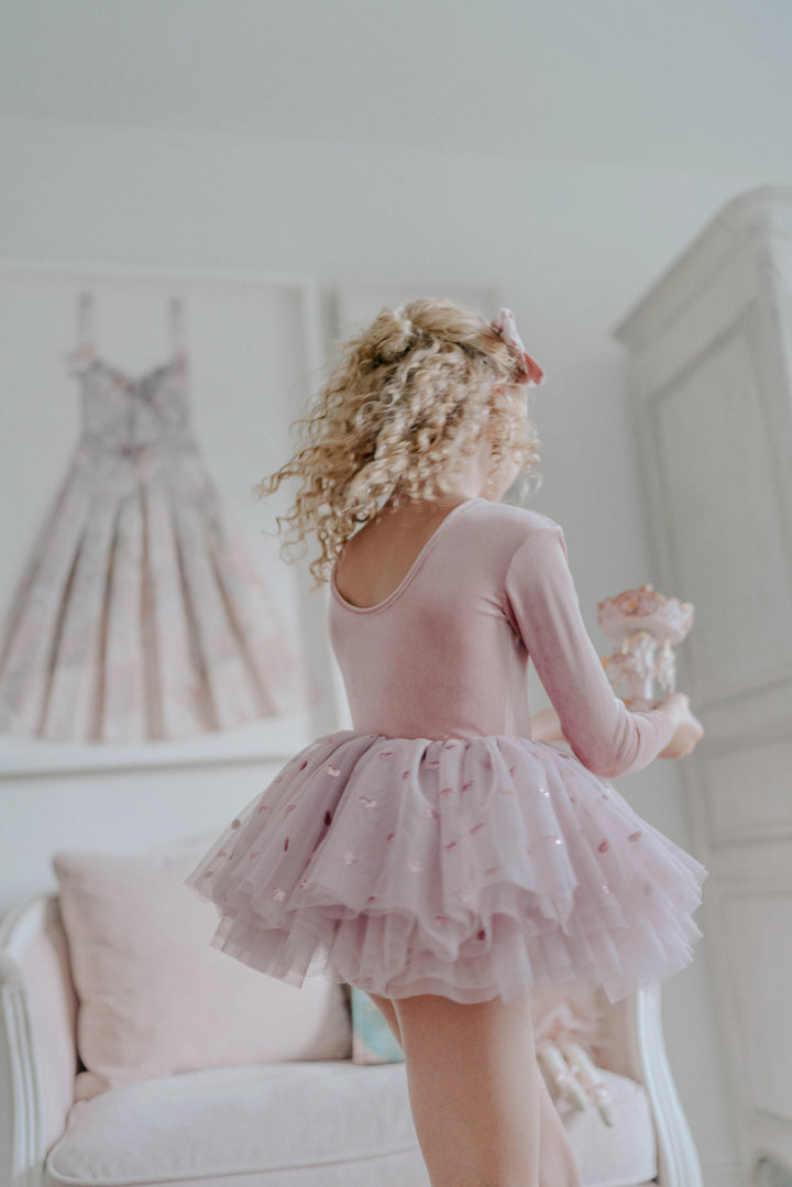 Girl twirling in rosewood heart sequin tulle tutu dress in softly lit indoor setting.