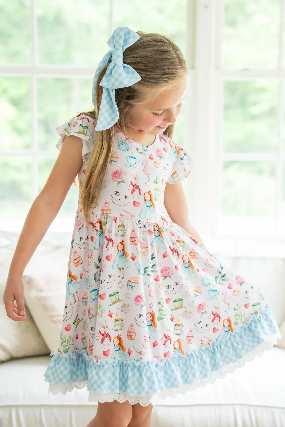Front view of child wearing Alice in Wonderland-inspired twirl dress with pink print, gingham hem, and lace details.
