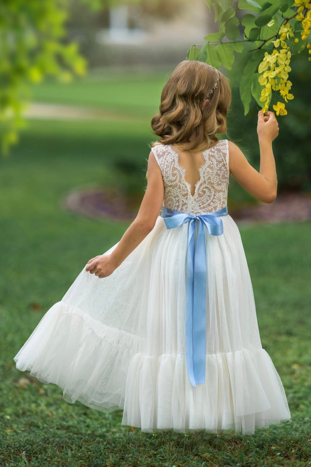 Antique ivory lace flower girl dress with V-back and layered tulle skirt photographed outdoors