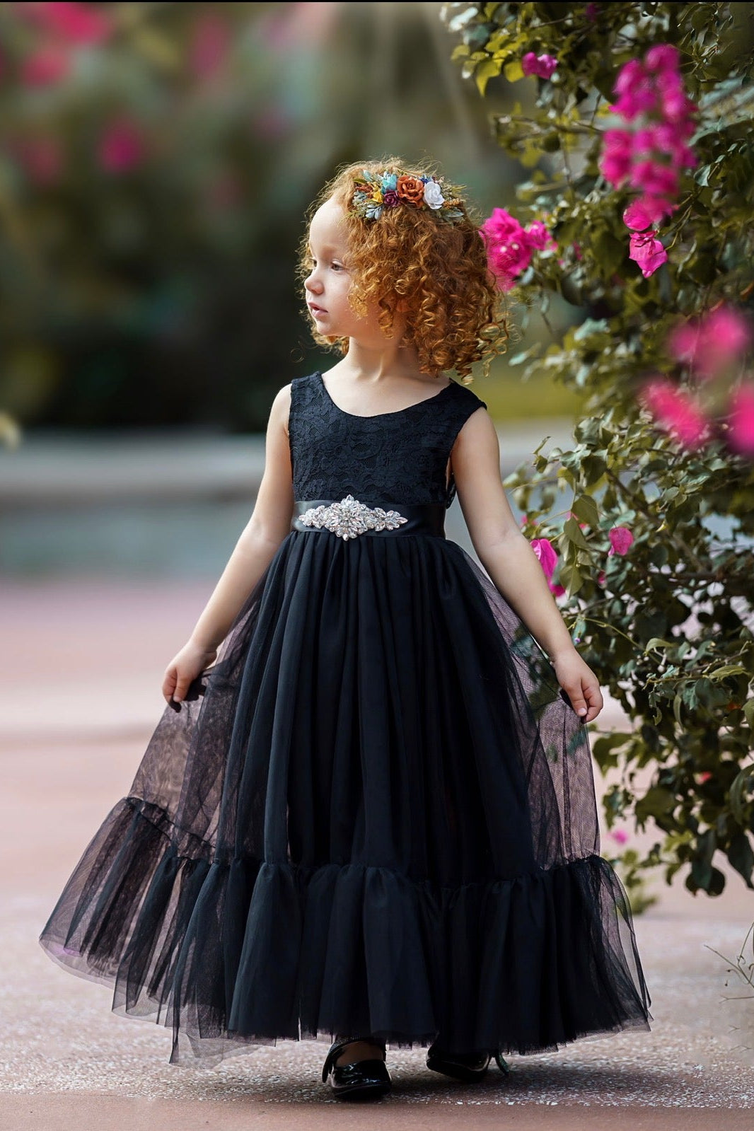 Black lace flower girl dress with V-back and layered tulle skirt photographed outdoors