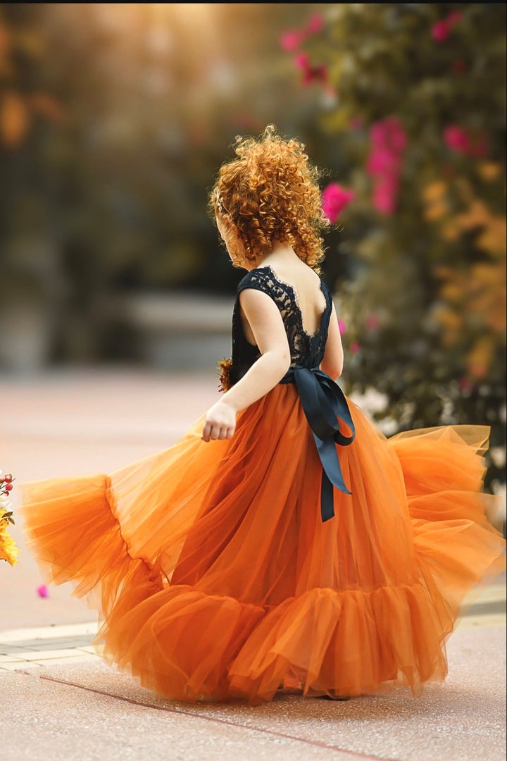 Two-tone flower girl dress with black lace bodice and burnt orange layered tulle skirt photographed outdoors