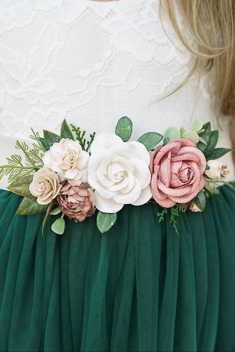 Floral belt with white, pink, and green flowers on a person wearing a white top and green skirt.