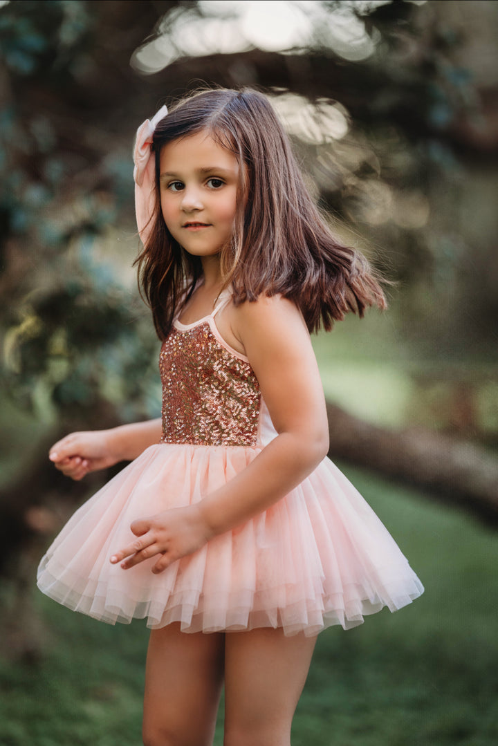 Side view of girl twirling in blush pink sequin tutu dress.