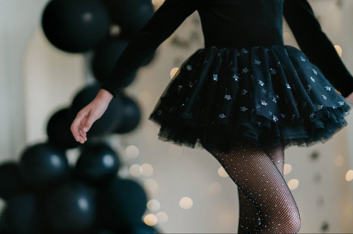 Close-up of layered black tulle skirt with silver star sequins on children's tutu dress.