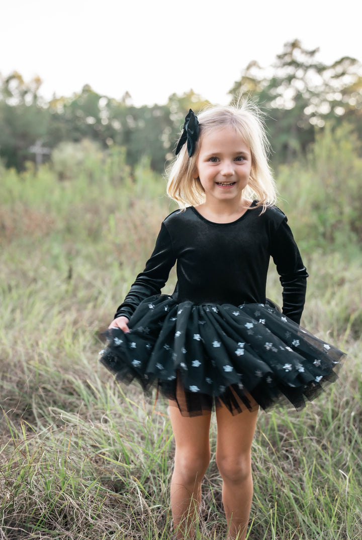 Black velvet long sleeve tutu dress for girls worn outdoors in natural light.