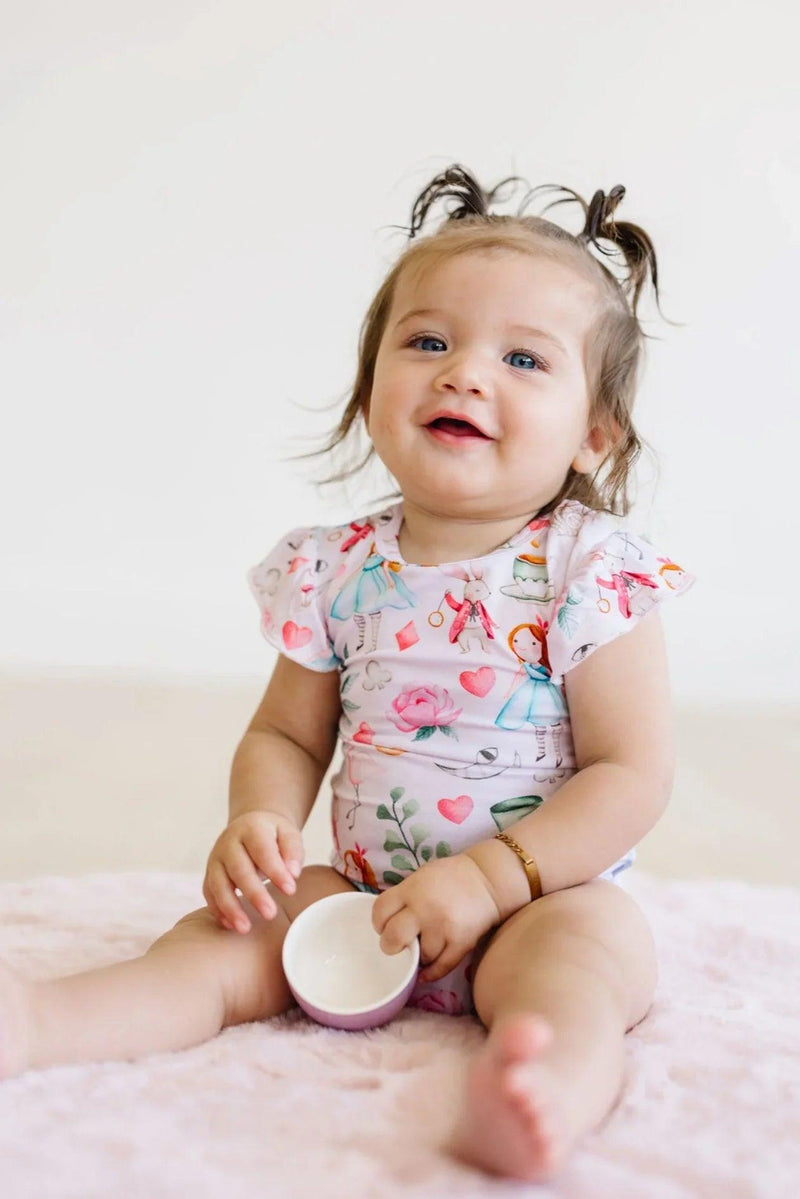 Baby girl sitting in bamboo ruffle sleeve bodysuit with snap bottom closure, soft and breathable for everyday wear.