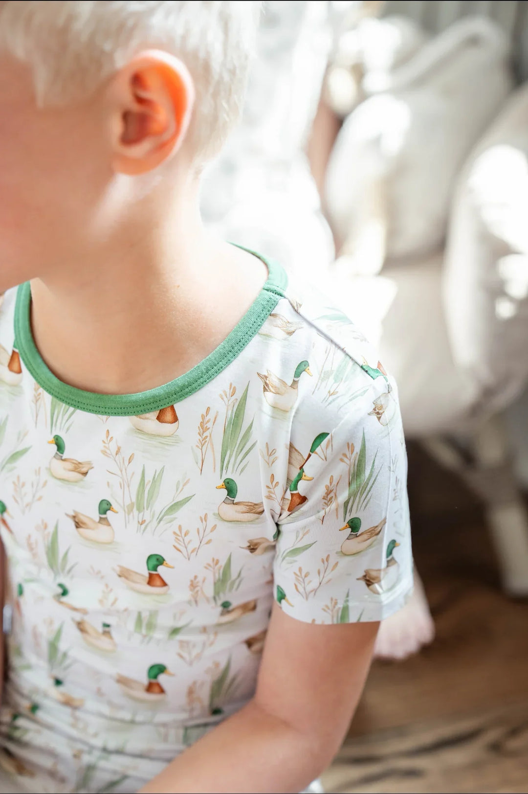 Toddler boy lounging in mallard duck bamboo pajamas, breathable two-piece sleepwear for summer.