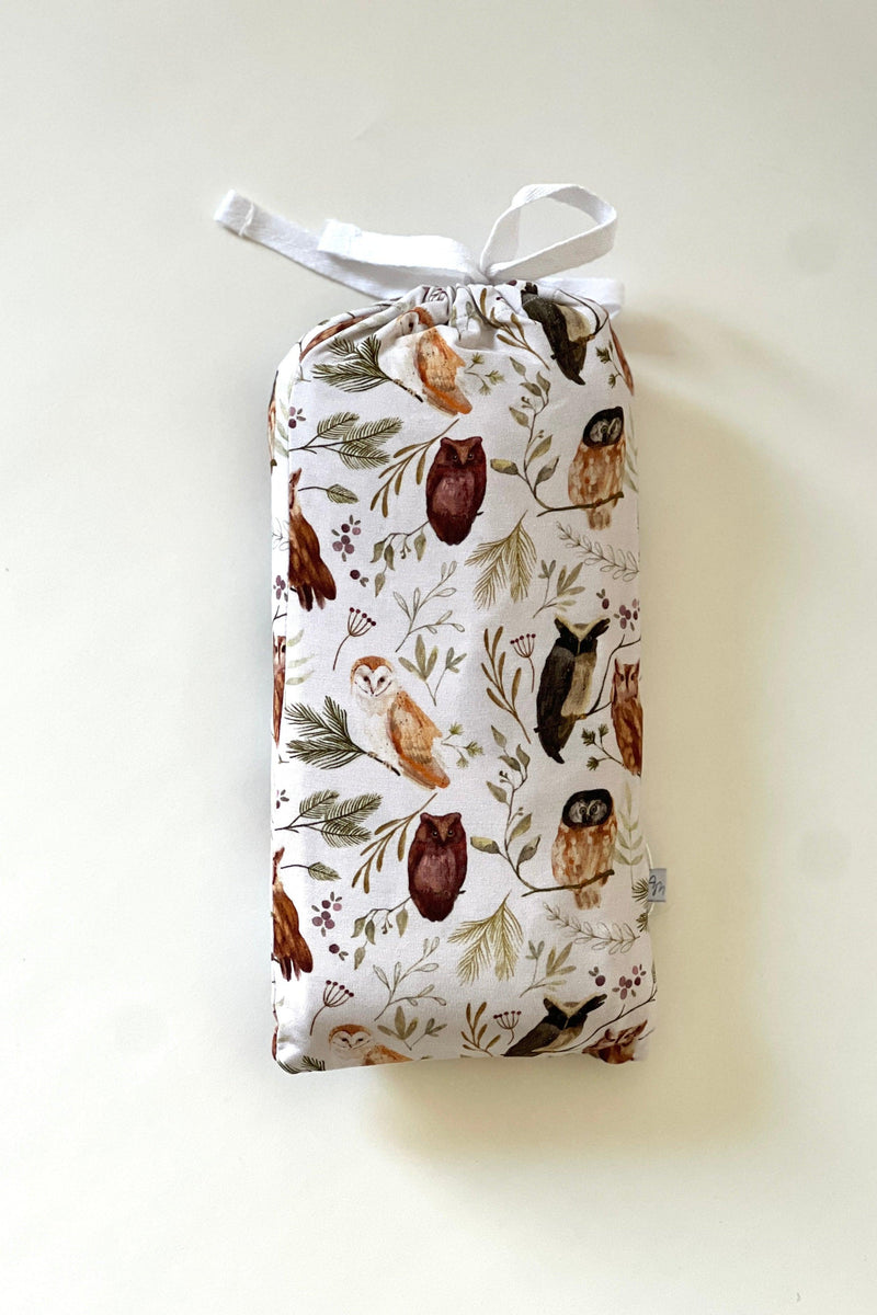 Sleepy Hollow Owls bamboo swaddle blanket folded inside coordinating drawstring pouch, made from the same printed fabric featuring baby owls on branches — soft, breathable, and gift-ready for baby showers and registries.