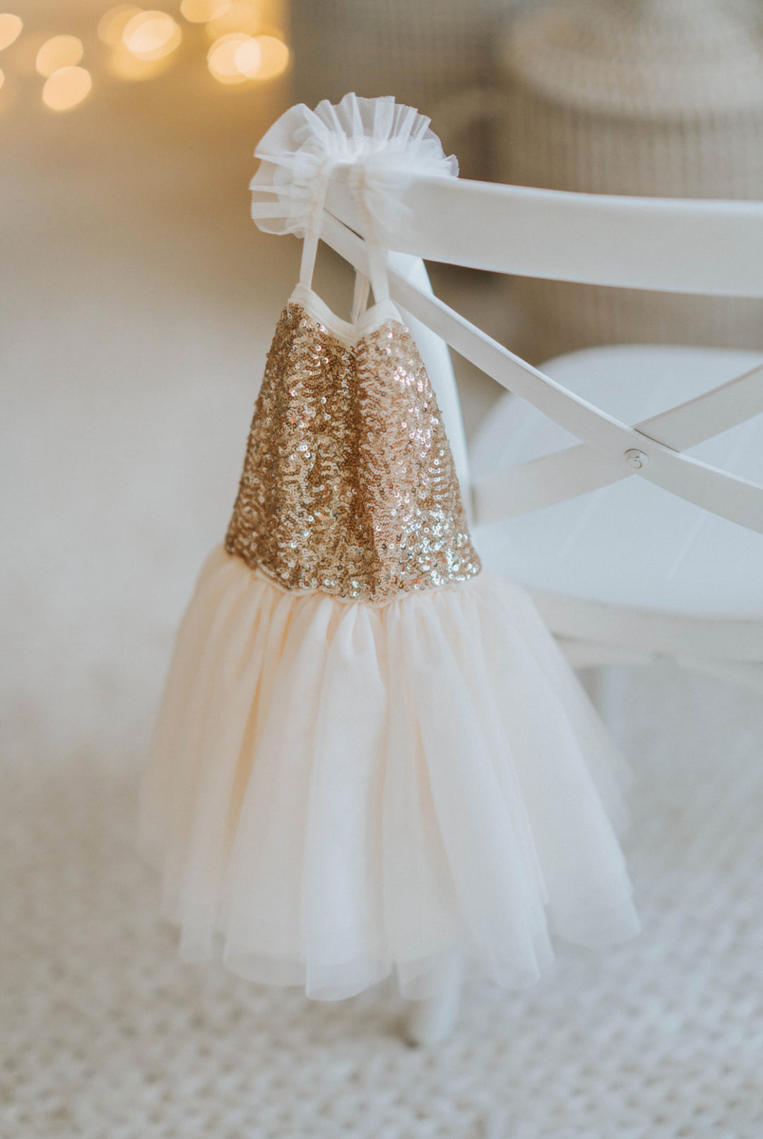 Cream and gold sequin tutu dress hanging on back of chair layered tulle skirt displayed