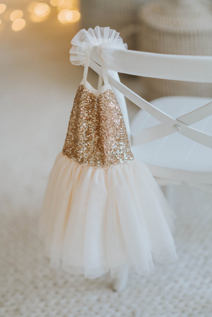 Cream and gold sequin tutu dress hanging on back of chair layered tulle skirt displayed