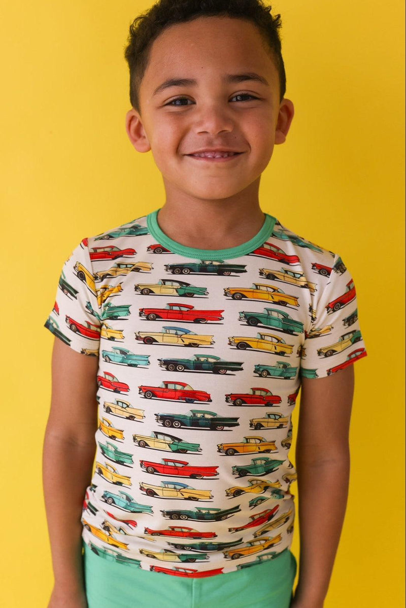 Close-up of retro classic cars graphic on kids’ short sleeve t-shirt, worn by a little boy — soft bamboo blend and vibrant colors.
