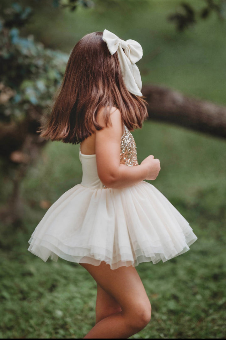 Toddler girl walking in cream and gold sequin tutu dress, soft layered tulle skirt twirling