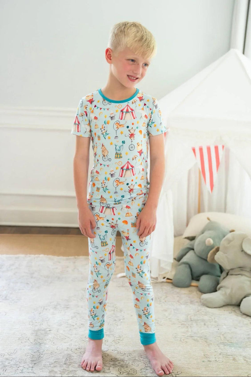 Little boy in front-facing view wearing Take Me to the Circus bamboo pajamas with short sleeves and long pants.