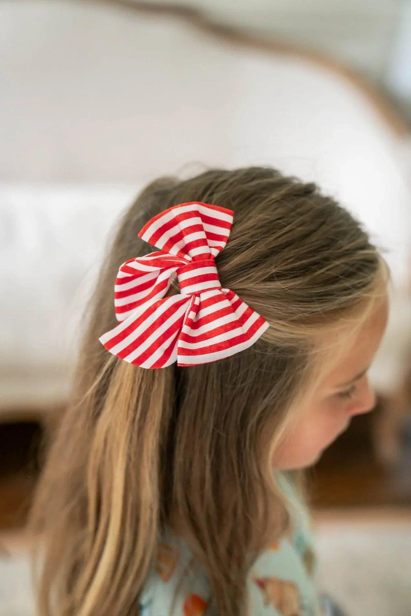 Small 4x4 red and white striped hair bow for girls, attached to a barrette clip, perfect for holiday or everyday wear.