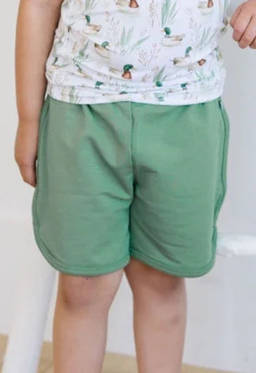 Unisex kids shorts in pine green French terry fabric, designed with a relaxed fit and elastic waistband.