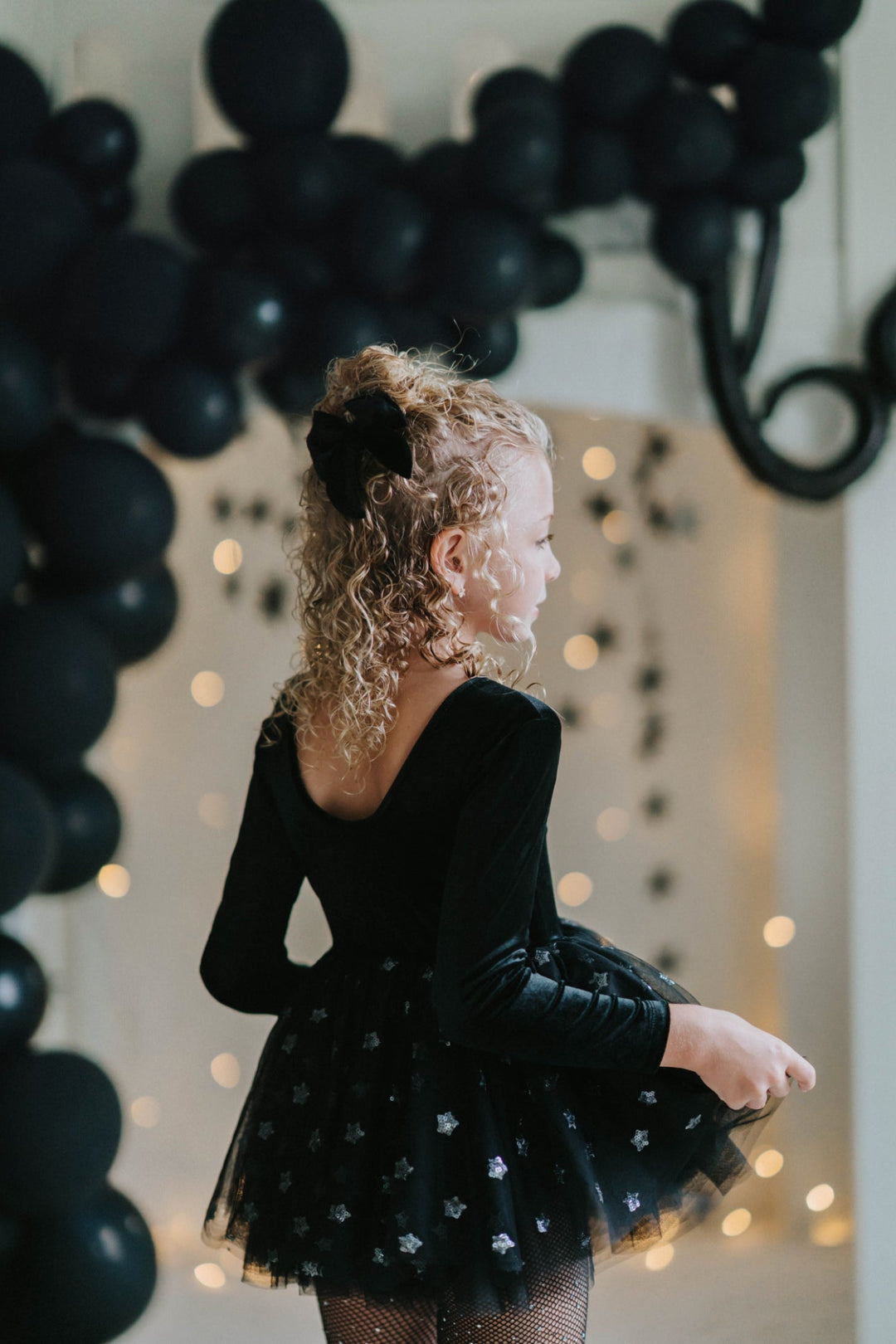 Girl twirling in black velvet star tutu dress with sparkling star details.