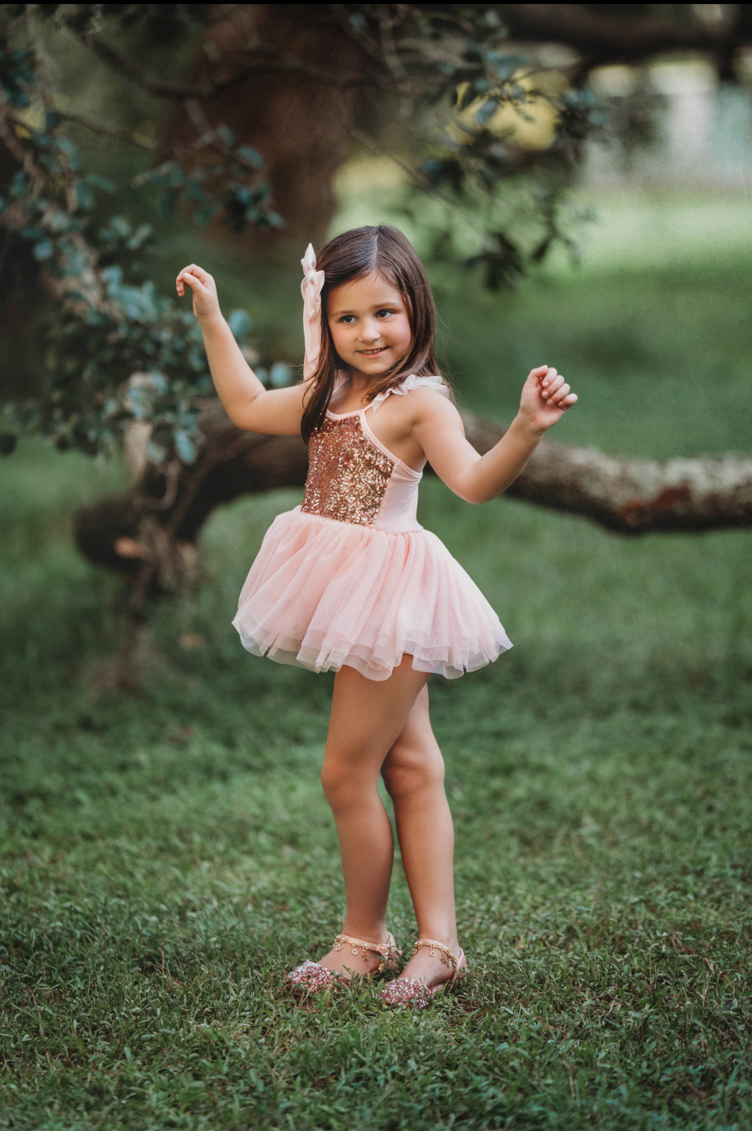 Child twirling joyfully in layered pink tulle party dress.
