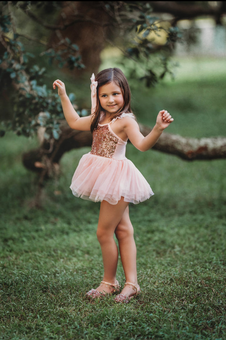 Child twirling joyfully in layered pink tulle party dress.