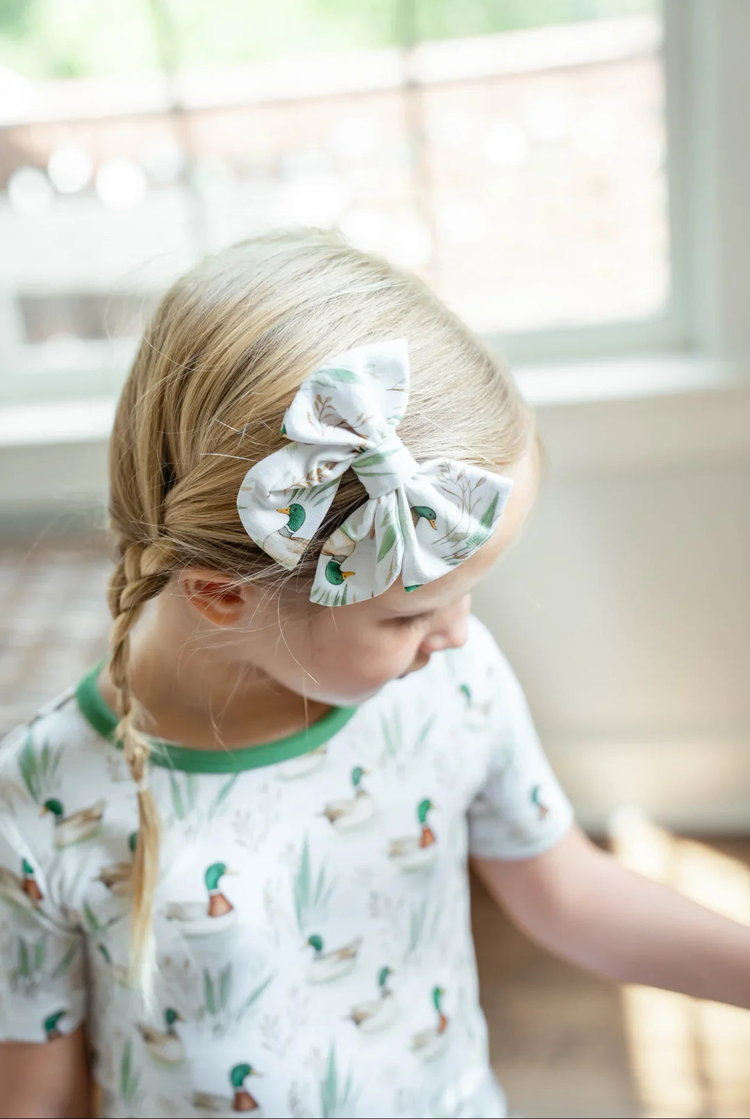 Small bamboo hair bow for girls in mallard duck print, featuring green ducks on a soft neutral background.