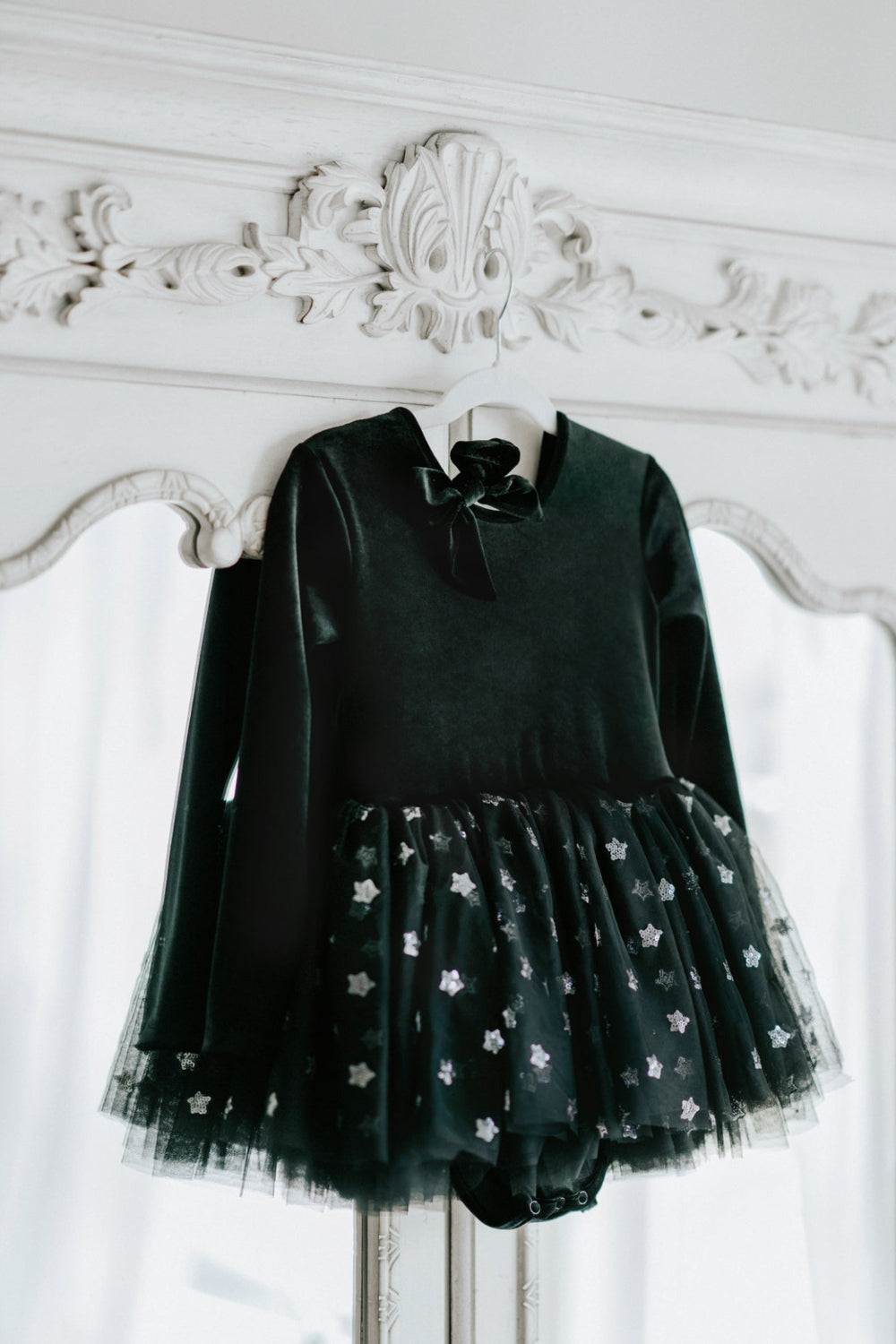 Black velvet long sleeve tutu dress with layered star tulle skirt on hanger.