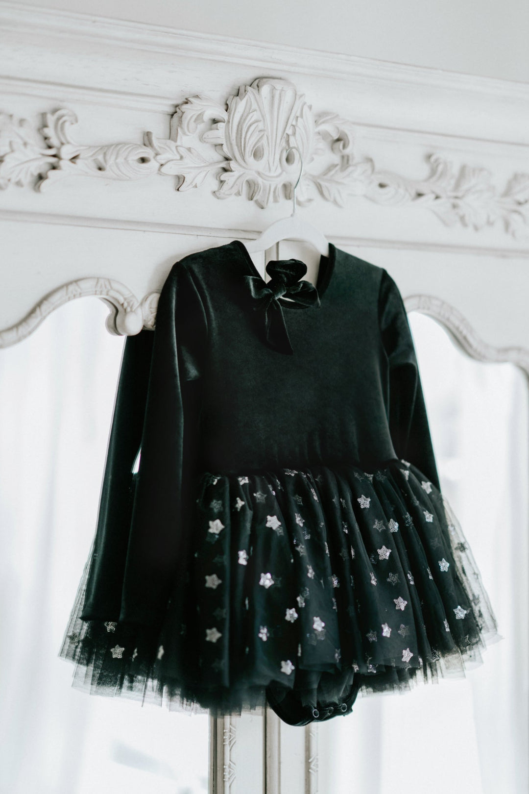 Black velvet long sleeve tutu dress with layered star tulle skirt on hanger.