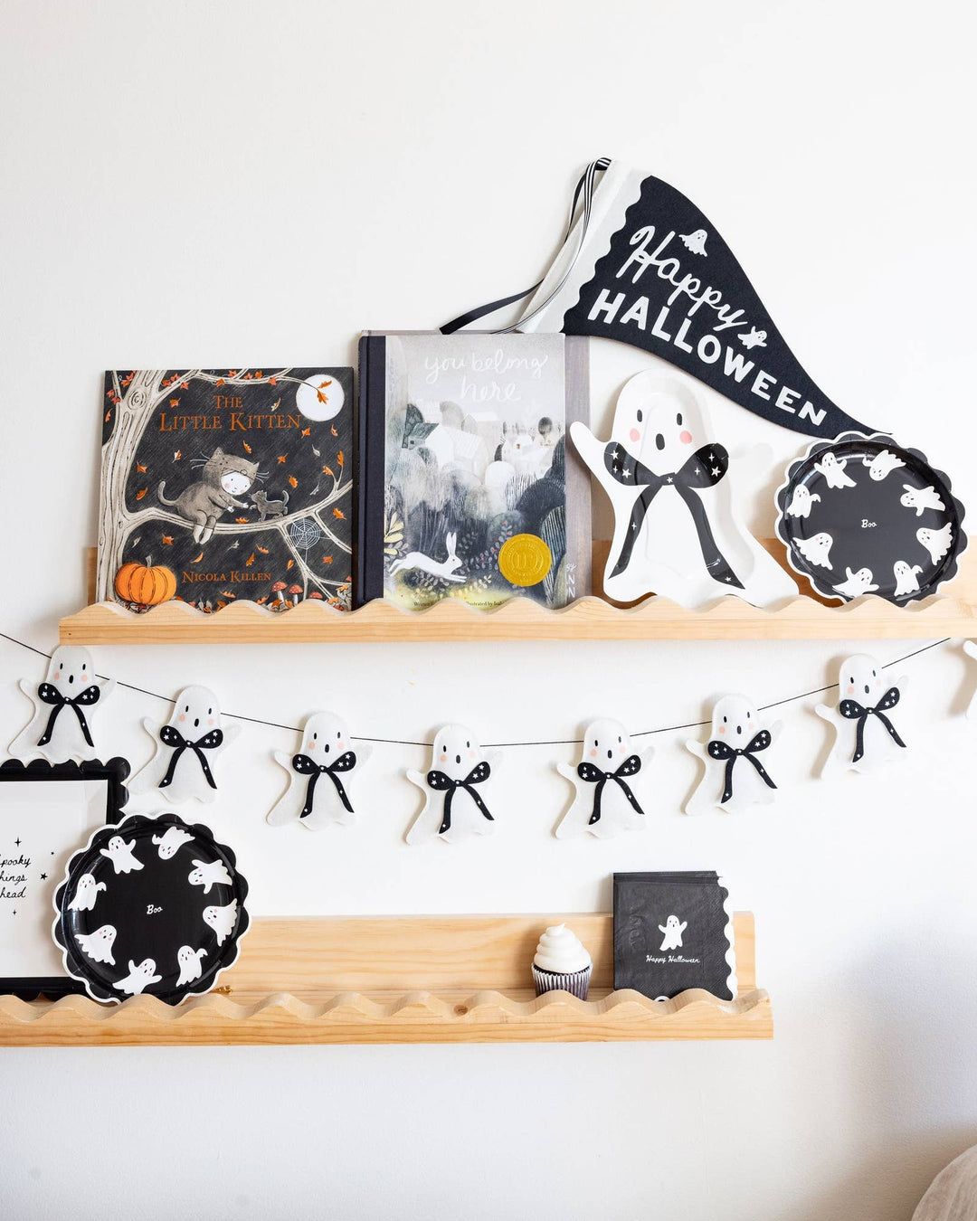 Little girl decorating for a Halloween party with My Mind’s Eye felt ghost garland hanging on the wall
