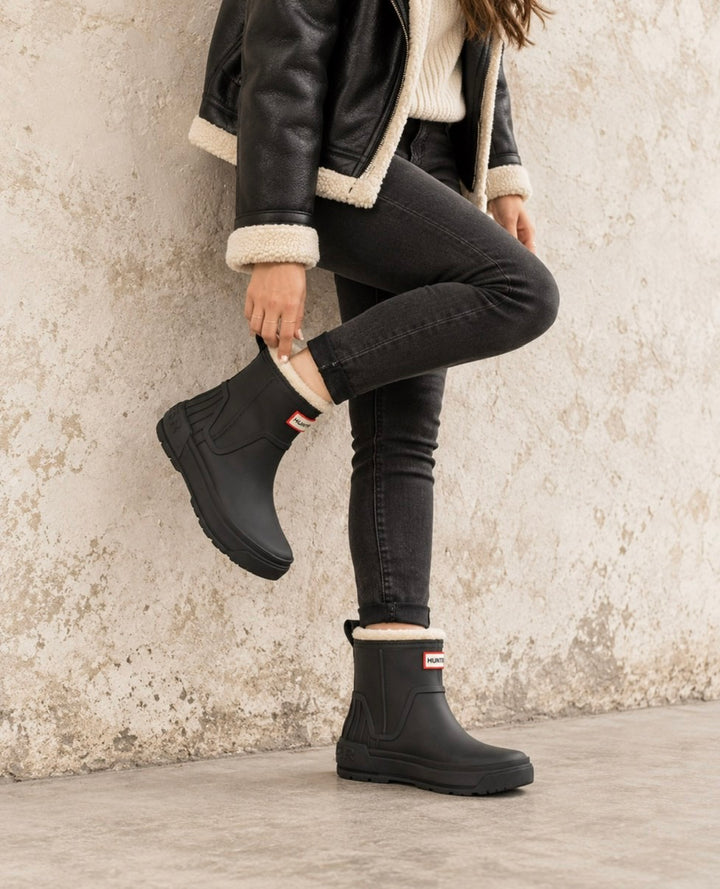 Hunter Women’s Willa black insulated waterproof booties styled with a shearling jacket and black jeans