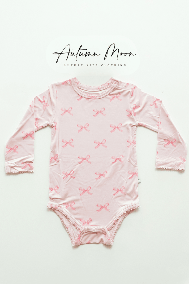 
Flat lay of pink bows bamboo long sleeve baby bodysuit featuring a soft light pink background with darker pink bow print — made from buttery soft bamboo viscose, ideal for baby girls.