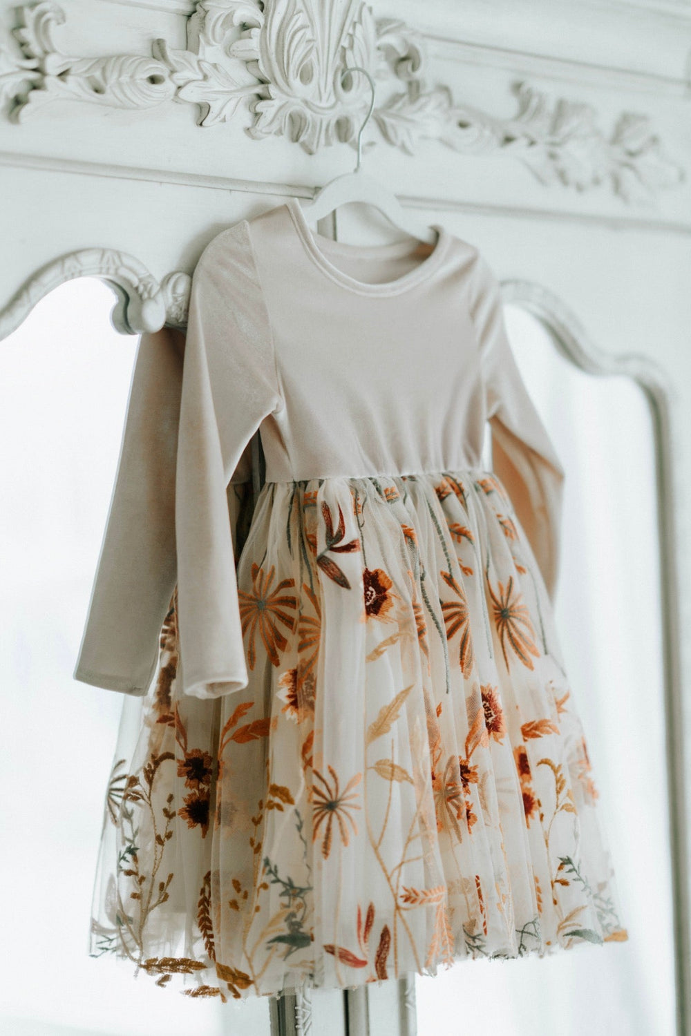 Champagne Velvet and floral dress hanging on dresses door.