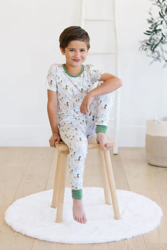Toddler boy sitting in mallard duck two-piece bamboo pajamas, soft breathable fabric for sleep and play.