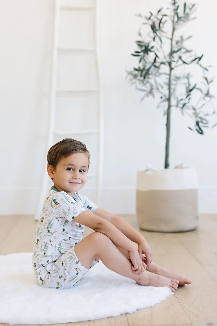 Toddler boy lounging in mallard duck bamboo pajamas, breathable two-piece sleepwear for summer.