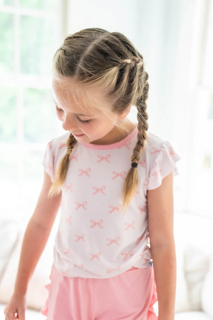 Little girl wearing pink bows ruffle sleeve bamboo T-shirt with rose ruffle shorts, styled for summer play.