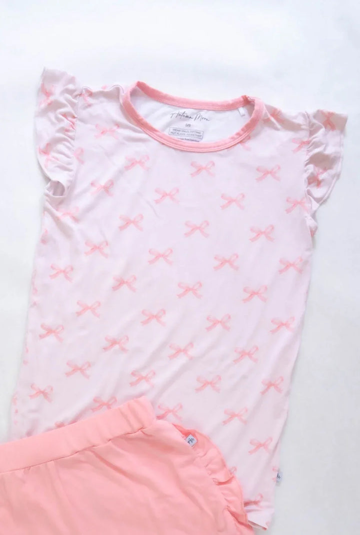 Girls pink bows bamboo graphic T-shirt with ruffle sleeves, shown in flat lay with rose collar and soft stretch fabric.