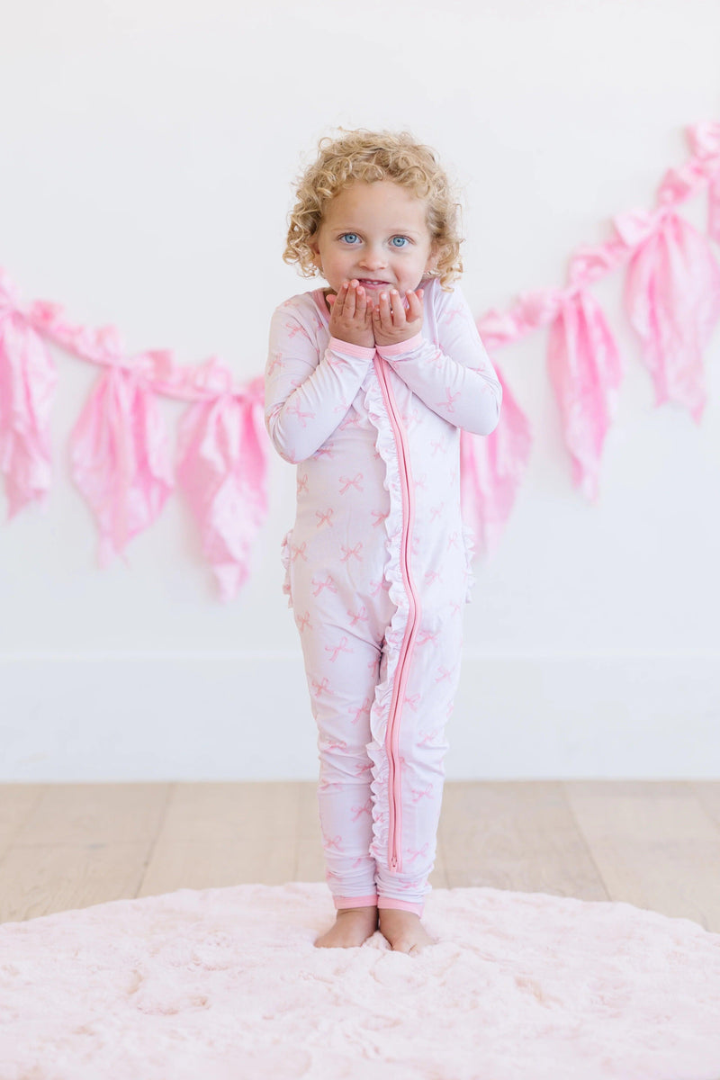 Front view of toddler in pink bows bamboo zipper pajamas, long sleeves with convertible feet and dual zipper.