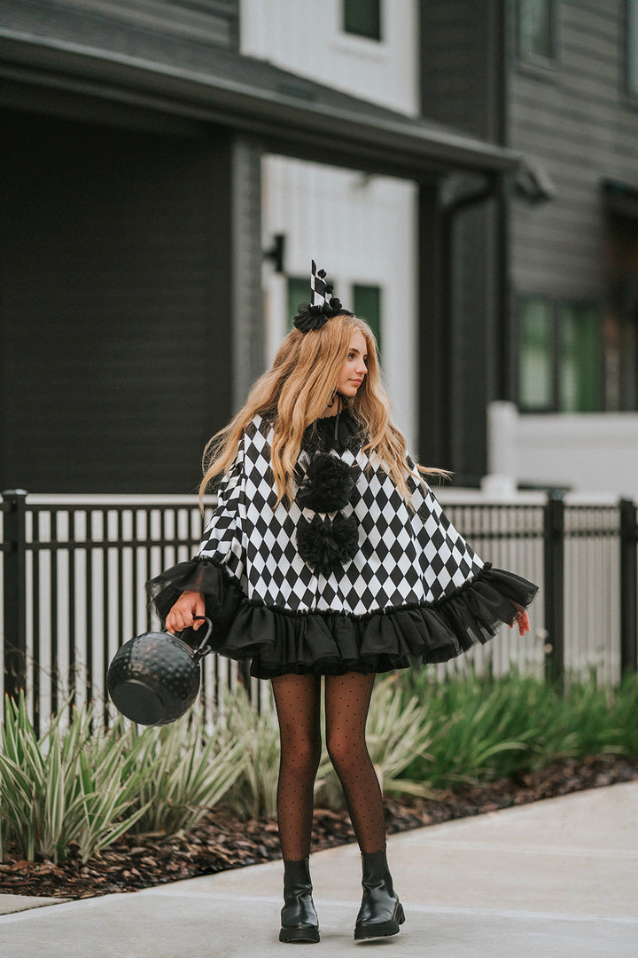 Pirouette harlequin clown cape in motion showing the full black and white satin silhouette and layered black tulle ruffle.