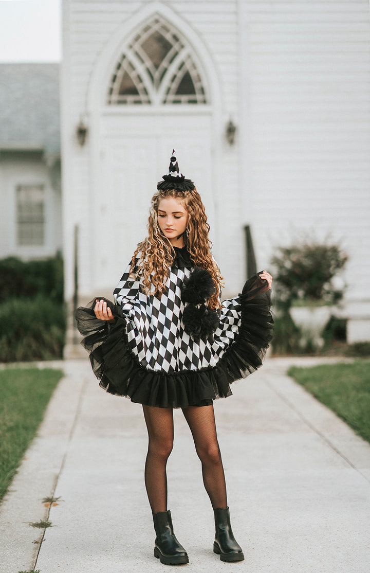 Pirouette Pierrette clown cape spread open to show the black and white diamond harlequin satin, full tulle ruffle and pom-pom details.