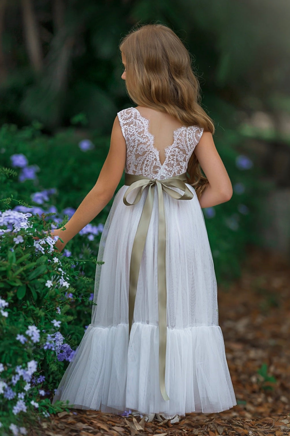 Soft white lace flower girl dress with V-back and layered tulle skirt photographed in garden setting