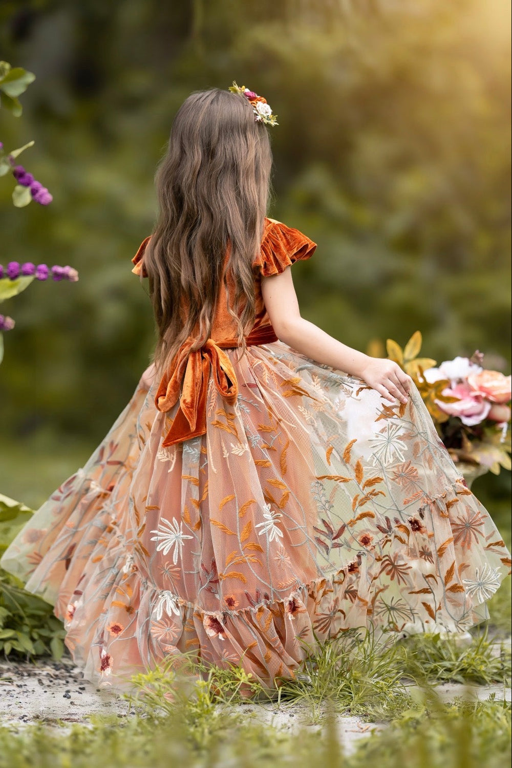 Back view of Virelle gown in burnt orange showing closed-back velvet bodice and sash tie