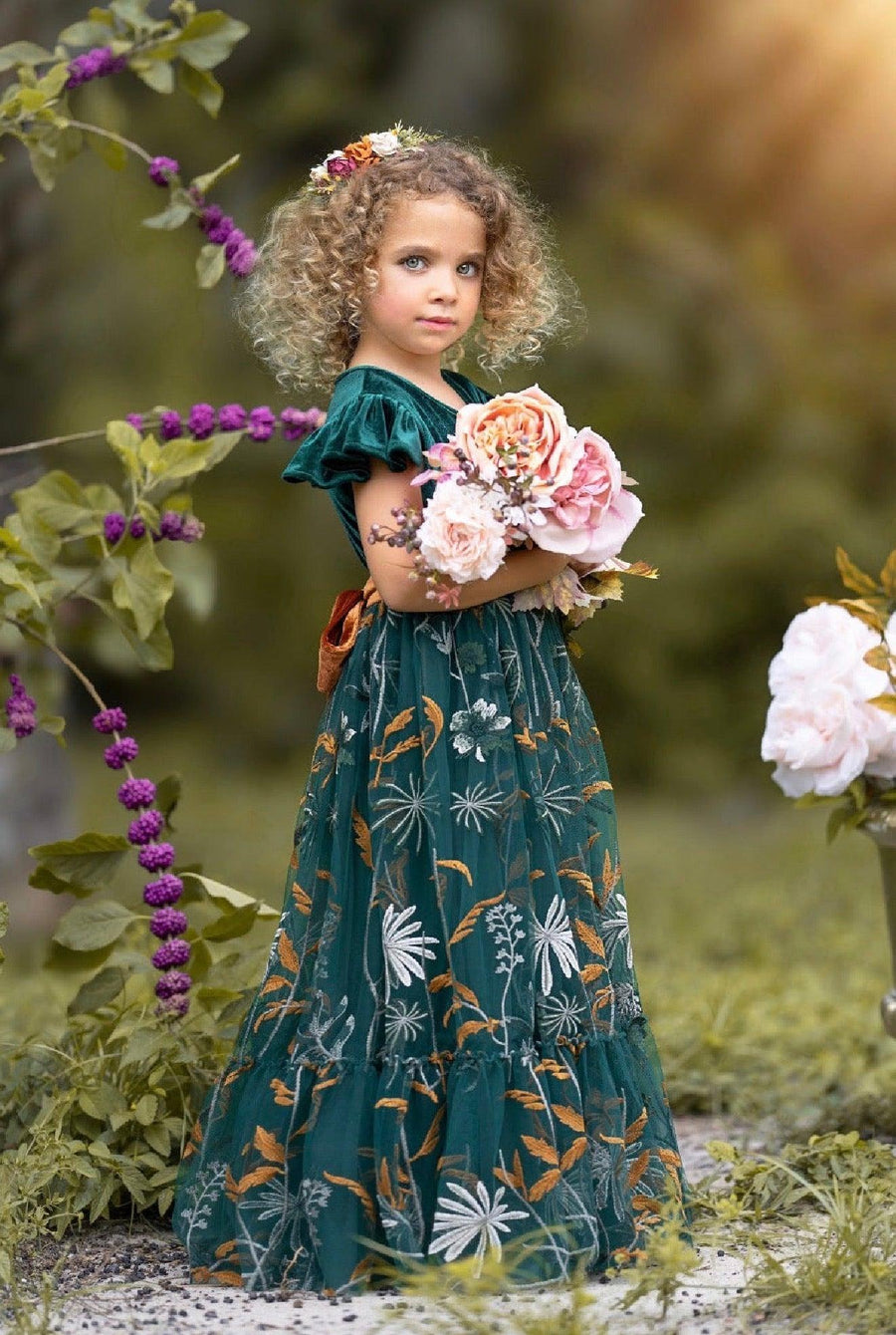 Side view of Virelle flower girl dress in forest green showing velvet ruffle sleeves and flowing floral embroidered tulle skirting.