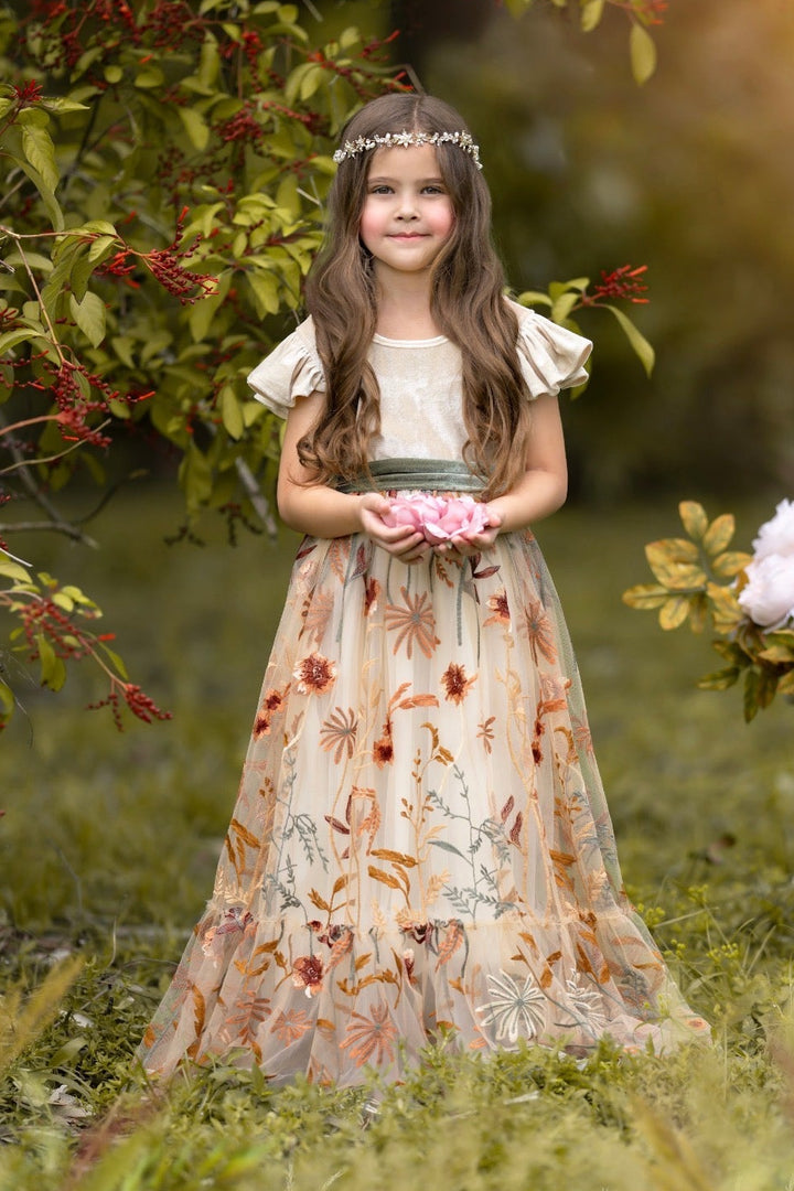 Girl wearing Virelle velvet flower girl dress in champagne with full-length embroidered floral tulle skirt outdoors