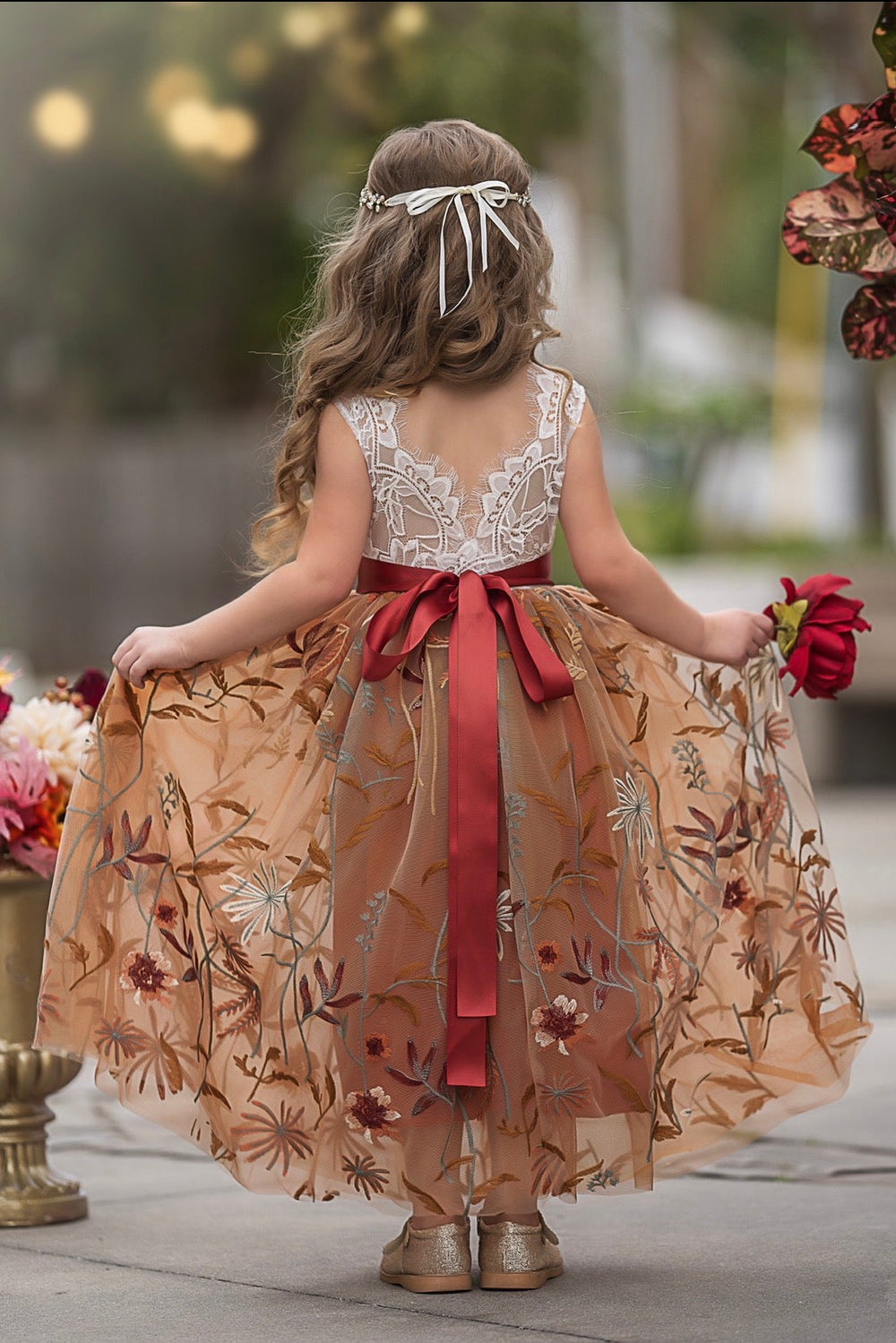 Back view of Ariella flower girl dress with V-shaped lace bodice and burnt orange floral embroidered tulle skirt for fall weddings

